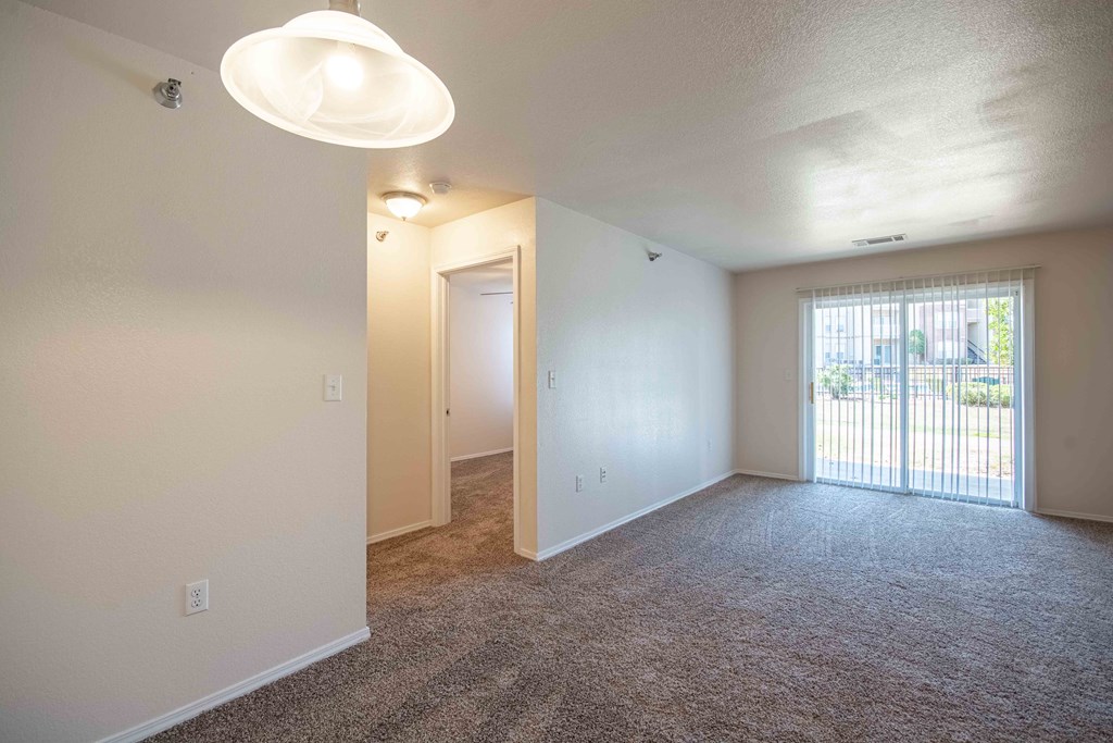 Living room with walkway to bedroom and glass doors with blinds