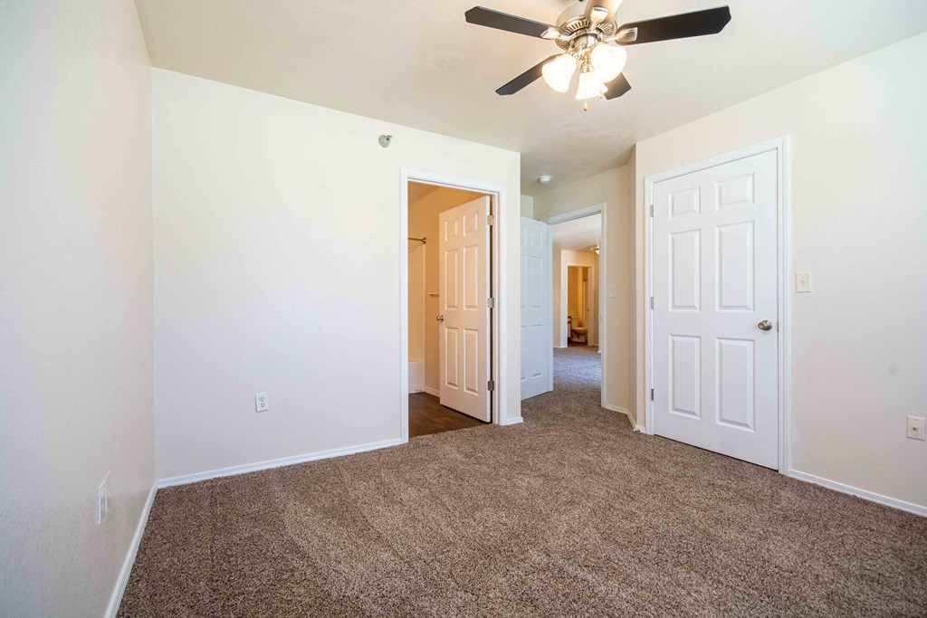Bedroom with carpet, closet, bathroom, and ceiling fan