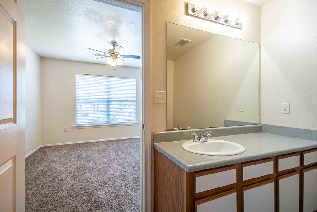 Bathroom connected to room with single sink, top light, big mirror