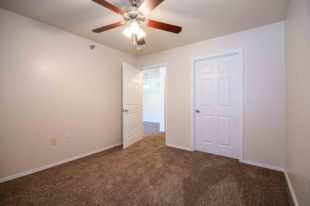 Bedroom with carpet, door, and ceiling fan