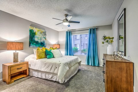 A bedroom with a bed, nightstand, and a painting on the wall.