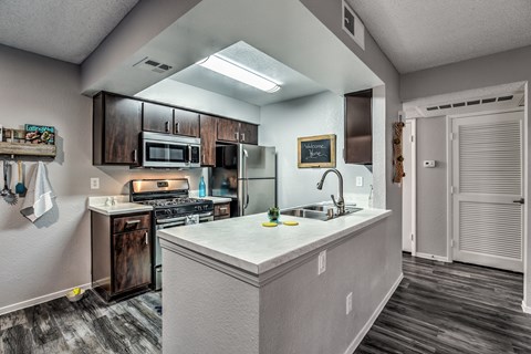 A kitchen with a white counter top and wooden cabinets.
