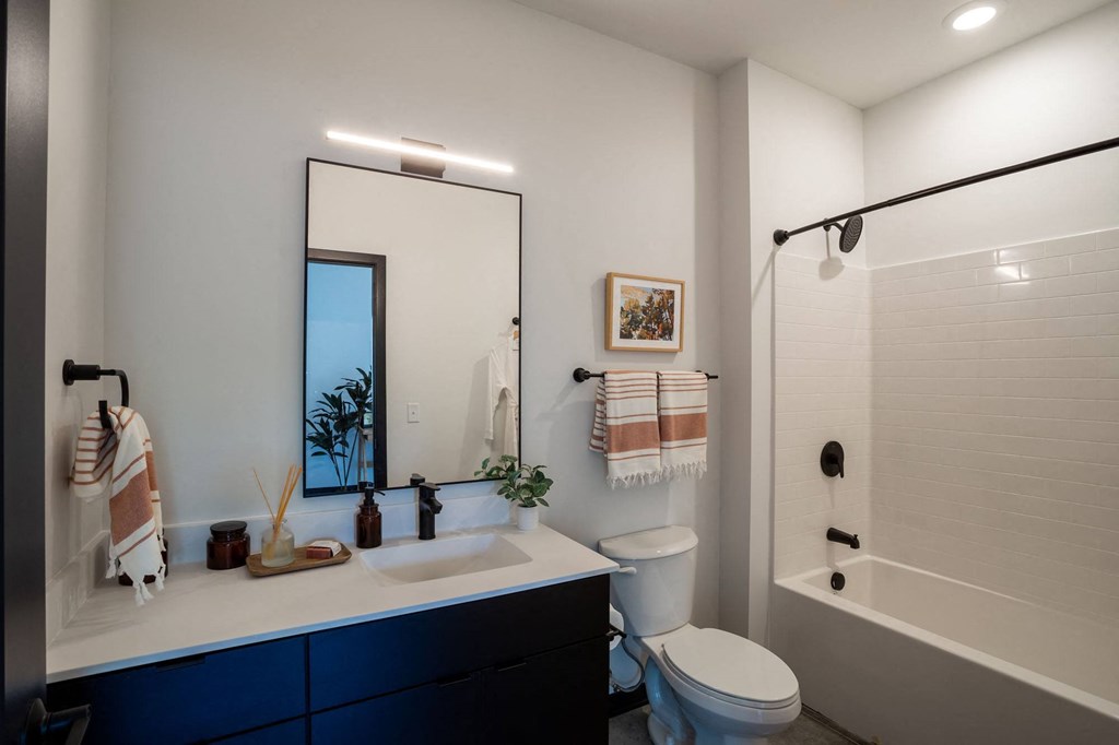 a bathroom with a large mirror and a toilet next to a bathtub