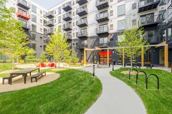 a park with benches and grass in front of an apartment building