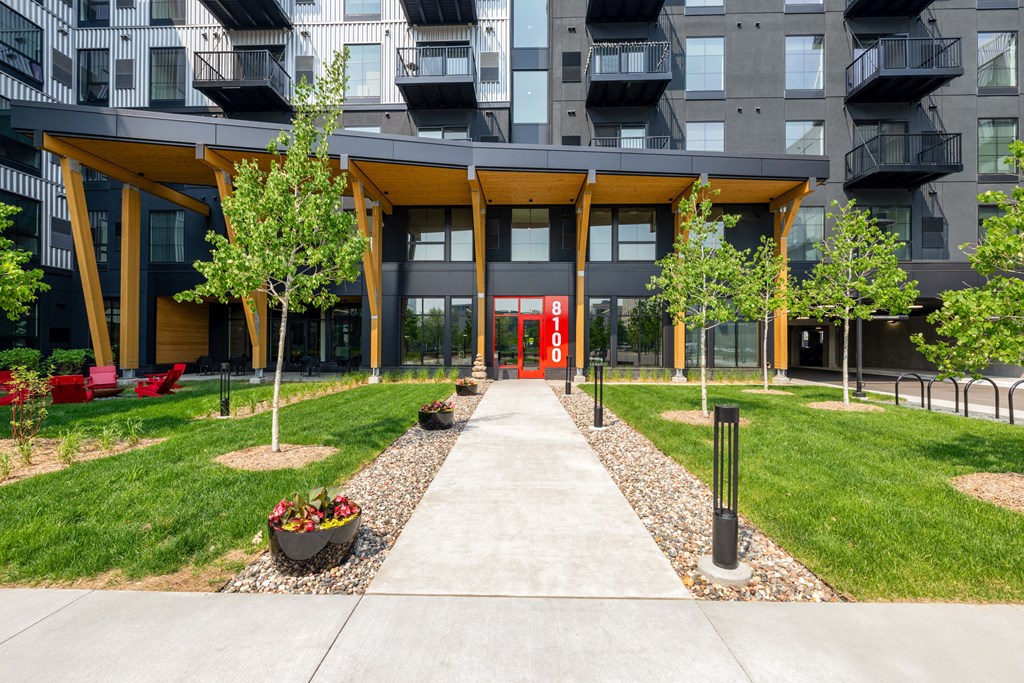 pathway leading to an apartment building with grass and trees