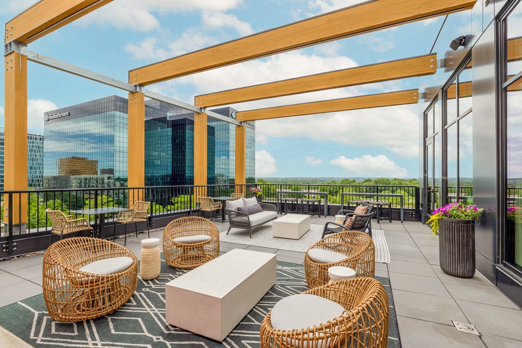 a rooftop patio with chairs and tables and a view of the city