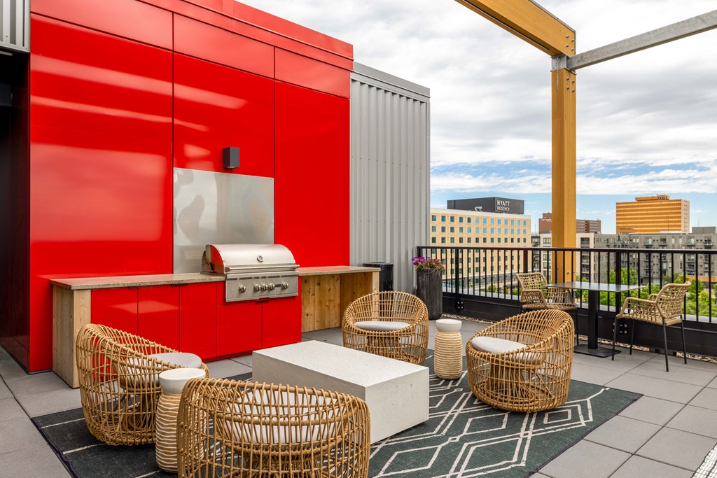 a rooftop patio with wicker chairs and a hot dog cart and a red wall