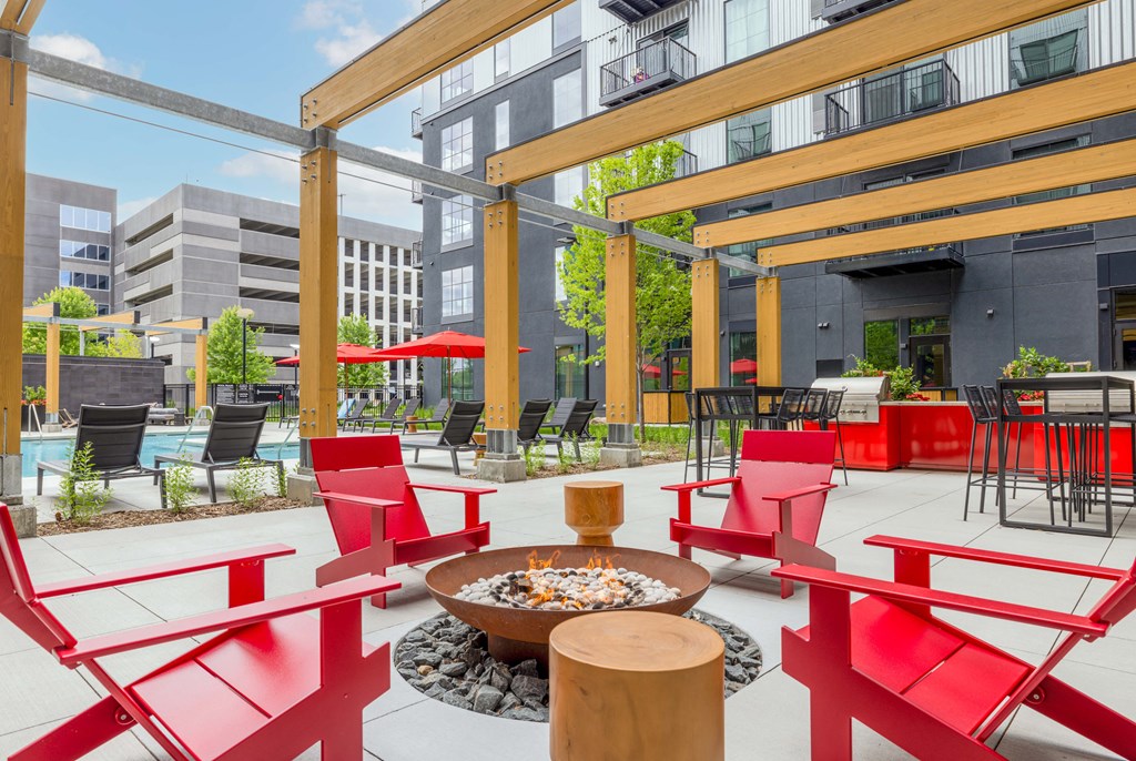 a patio with red chairs and tables and a fire pit