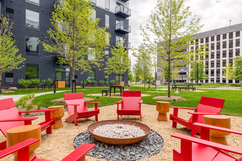 a courtyard with red chairs and a fire pit