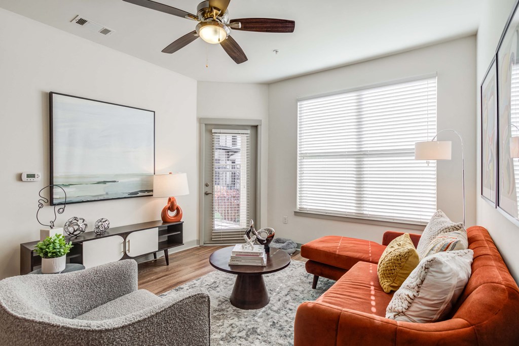 Modern apartment living room with orange sofa, gray armchair, and stylish decor.