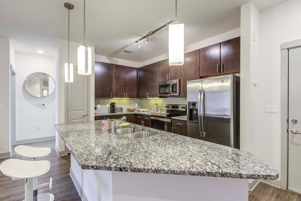 Modern kitchen with granite countertops, stainless steel appliances, and dark wood cabinets.
