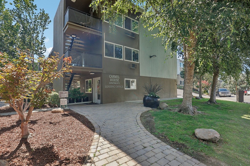 a building with a walkway and trees in front of it