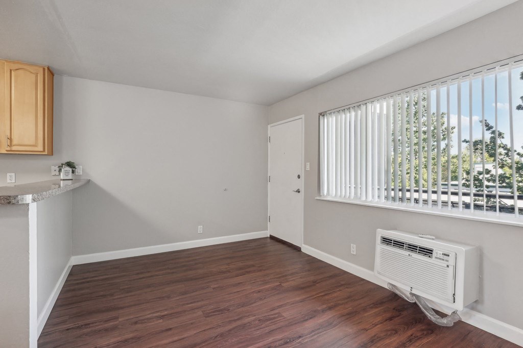 Townhomes in Walnut Creek, CA - Carmel House - Living Room with Wood-Inspired Flooring, Large Window, and Air Conditioning Unit.