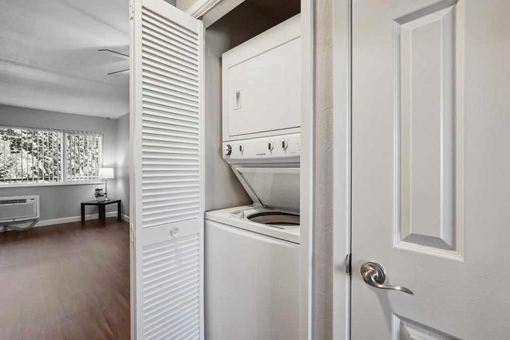 a small kitchen with white appliances and a door to the laundry room