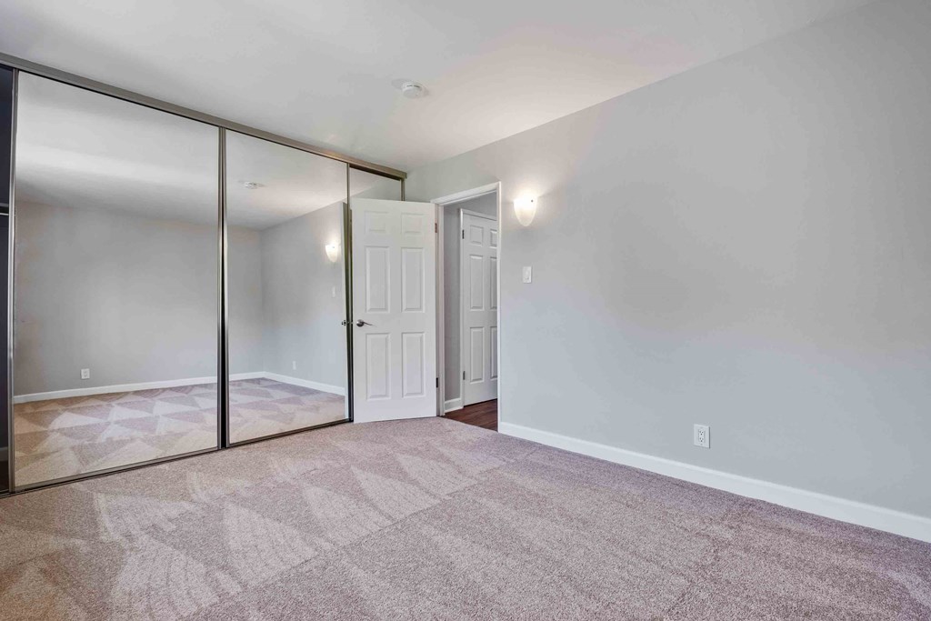 One-Bedroom Apartments in Walnut Creek, CA - Carmel House - Bedroom with Carpeting and Closet with Mirrored Sliding Doors.