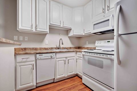 a kitchen with white cabinets and appliances and a counter top