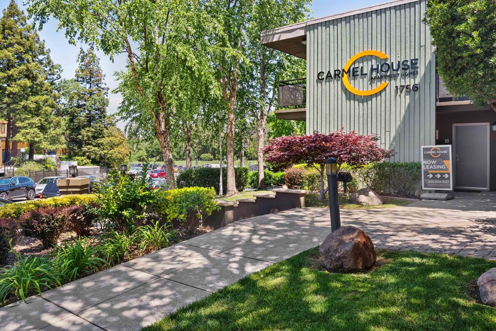 a sidewalk in front of a cafe house with a sign on the side