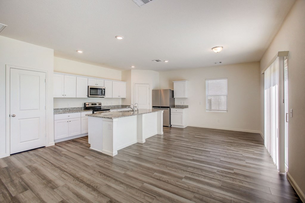 an empty kitchen with white cabinets and a counter top