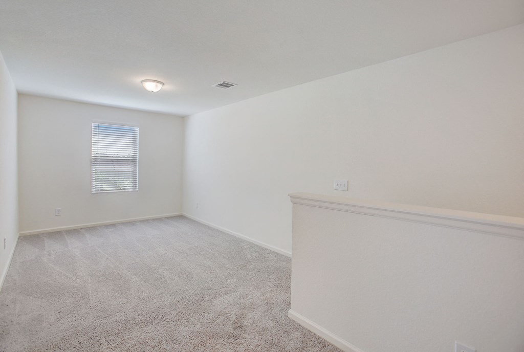 an empty room with white walls and carpet and a window