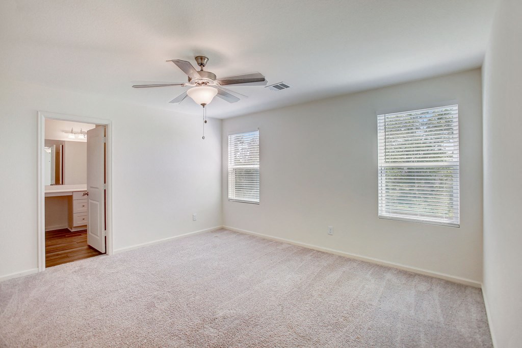 an empty living room with a ceiling fan