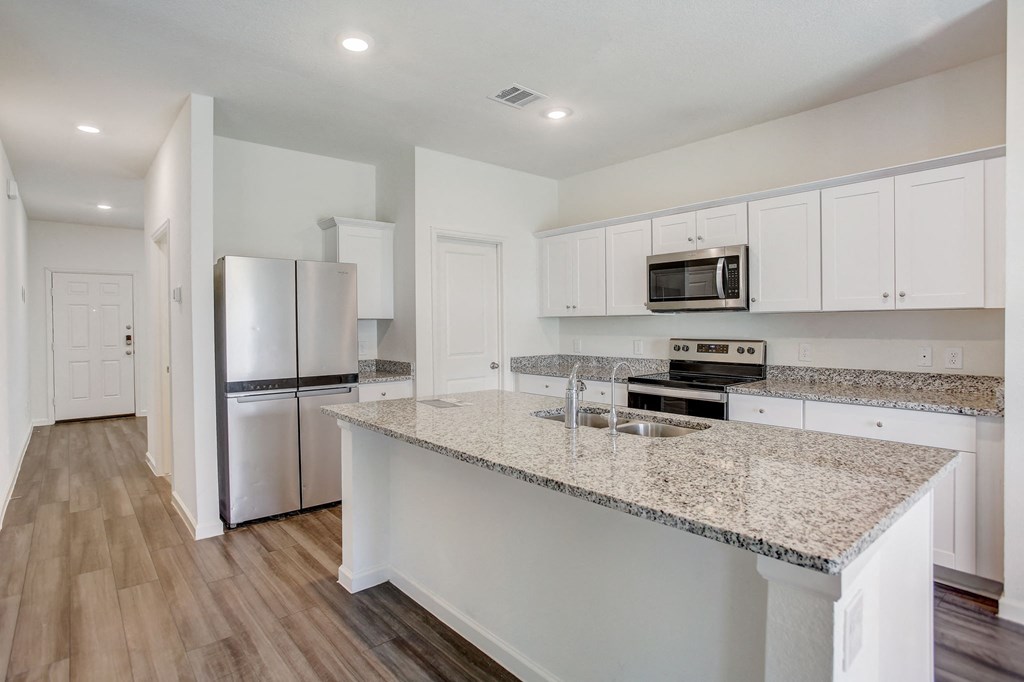a kitchen with a granite counter top and a stainless steel refrigerator