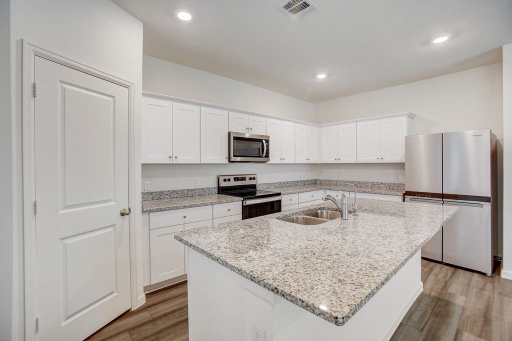 a kitchen with white cabinets and a granite counter top