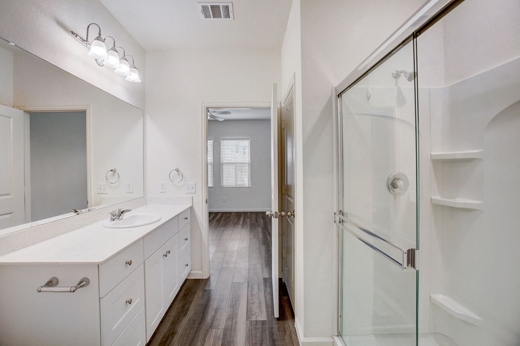 a white bathroom with a glass shower and a sink and a mirror