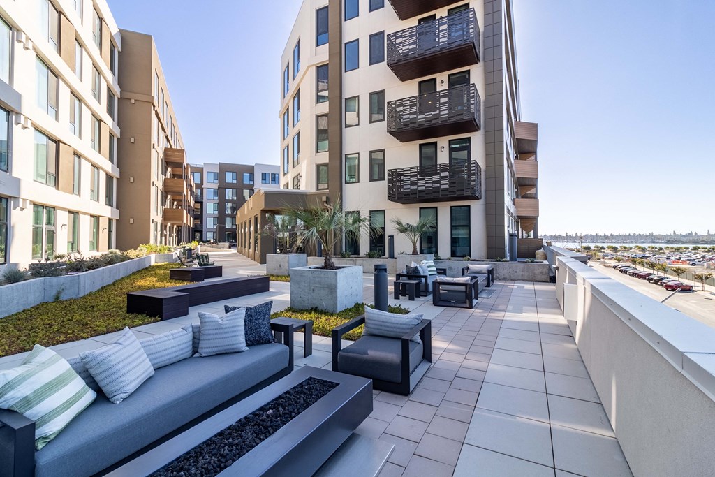a communal terrace with couches and tables in front of an apartment building