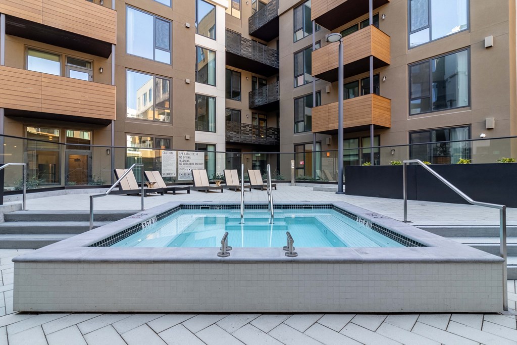 a pool with chairs in front of an apartment building