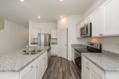 A kitchen with white cabinets and granite countertops.