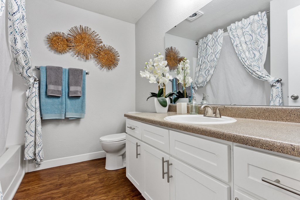 A bathroom with a toilet, sink, and a mirror. at Cedar Crest, Beaverton, 97078