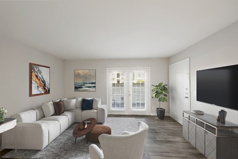 A living room with a white couch, a brown chair, a coffee table, a television, and a painting on the wall.