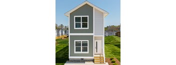 A small house with a grey and white exterior and a white door.