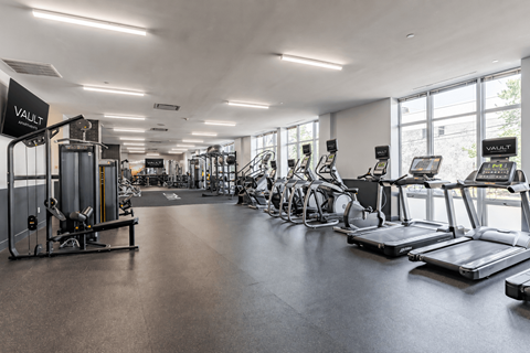 A gym with a variety of equipment including treadmills, weights, and exercise bikes.