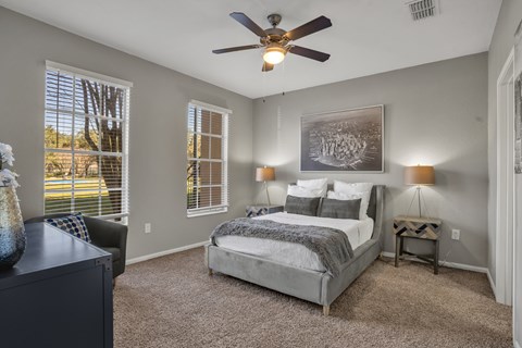 A bedroom with a bed, a dresser, and a ceiling fan.