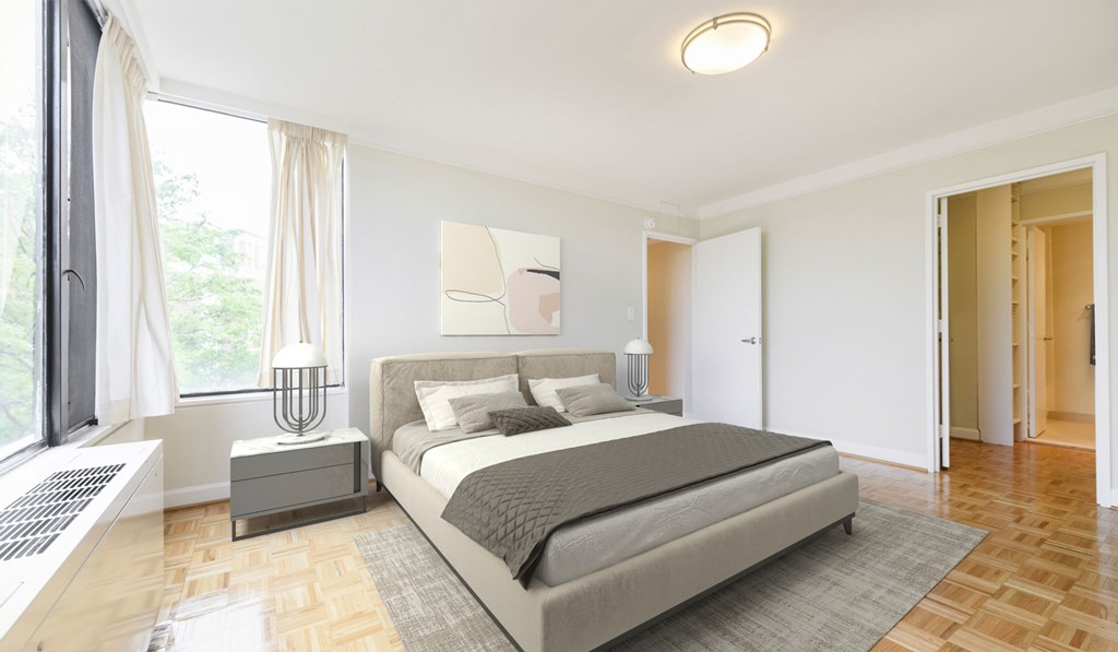 A bedroom with a large bed and a window with curtains.