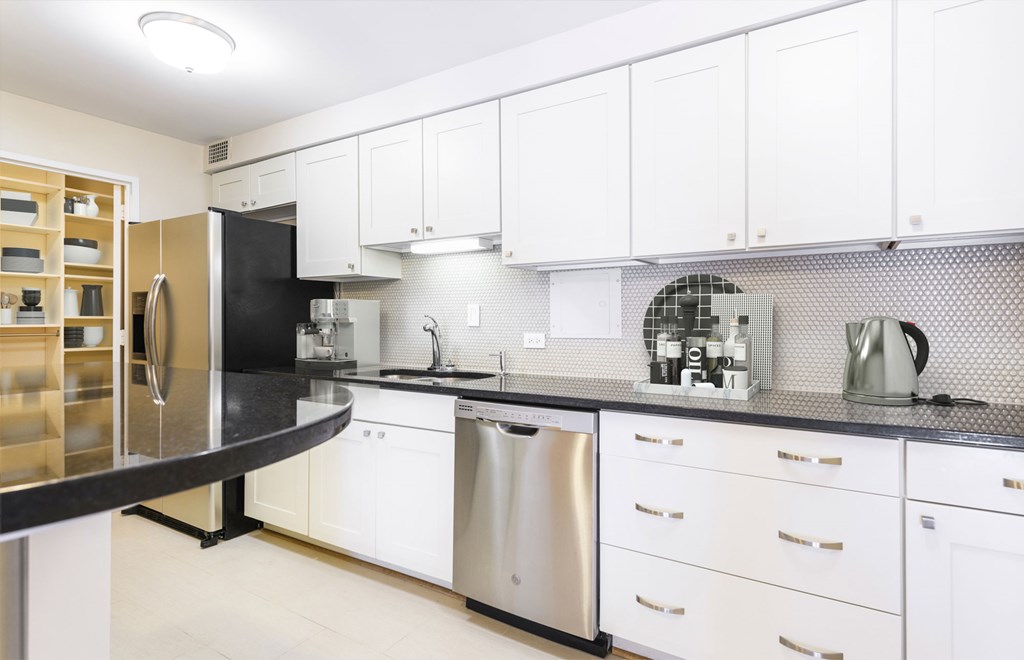 A modern kitchen with white cabinets and black countertops.