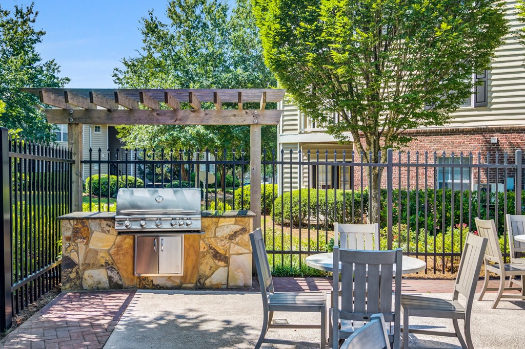 a patio with a grill and tables and chairs
