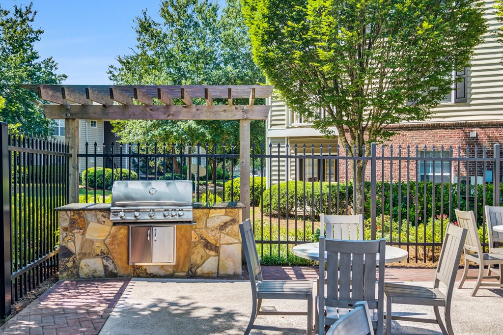 a patio with a grill and tables and chairs