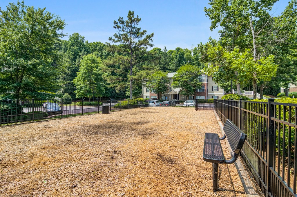 a park bench in front of a fenced in area with trees