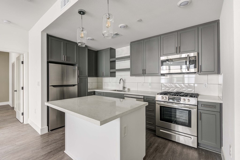 2 BR Apartments In Whitter, CA - Cierra - Kitchen With Stainless Steel Appliances, Kitchen Island, Sleek Grey Cabinetry, And Vinyl Plank Flooring