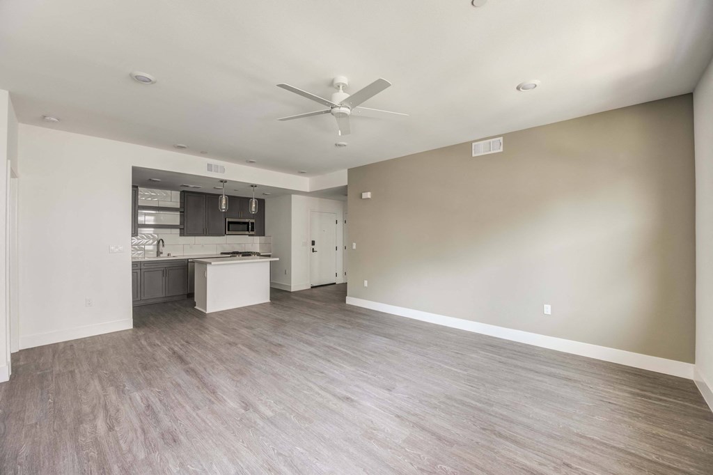 an empty living room and kitchen with a ceiling fan