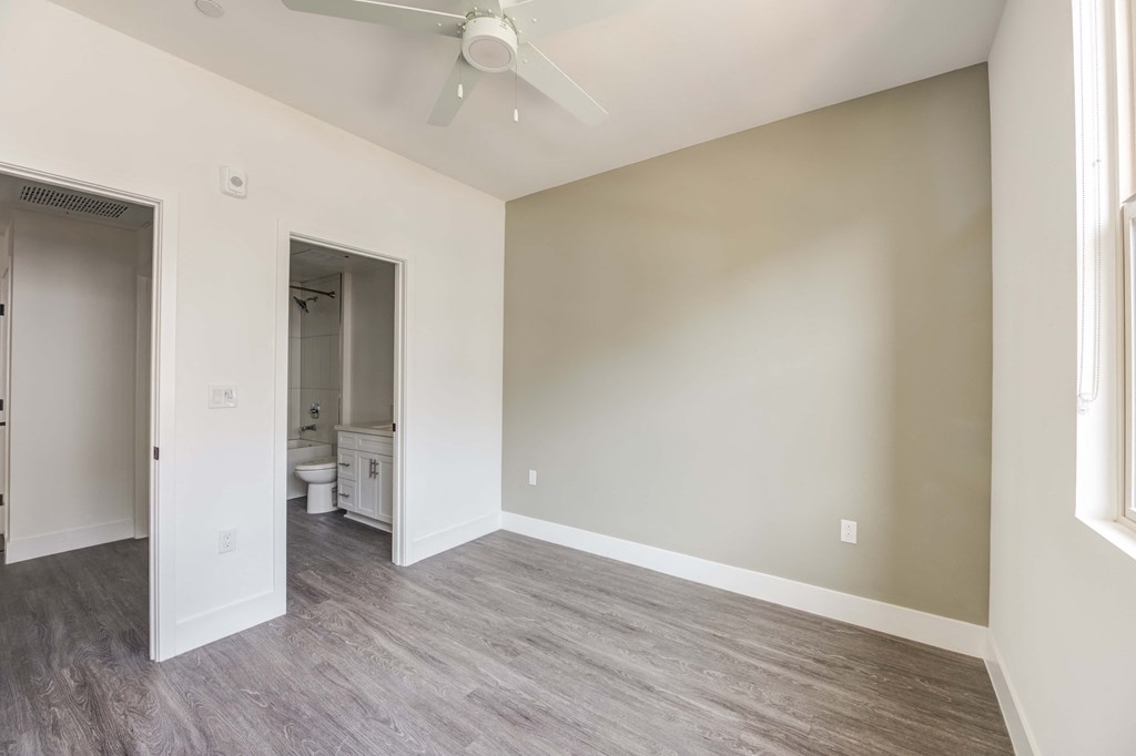 an empty living room with wood flooring and a ceiling fan