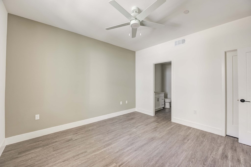an empty living room with white walls and a ceiling fan