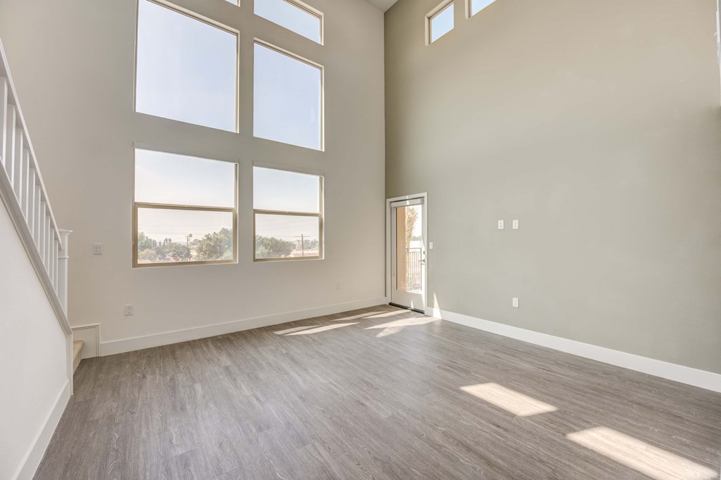 an empty living room with large windows and wood flooring
