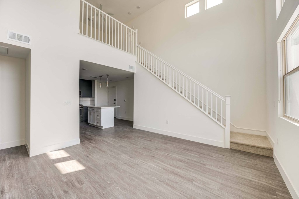 Apartments In Whitter, CA For Rent - Cierra - Spacious Living Room With High Ceiling, Multiple Windows For Natural Sunlight, Vinyl Plank Flooring, And Direct Access To The Kitchen And Stairs