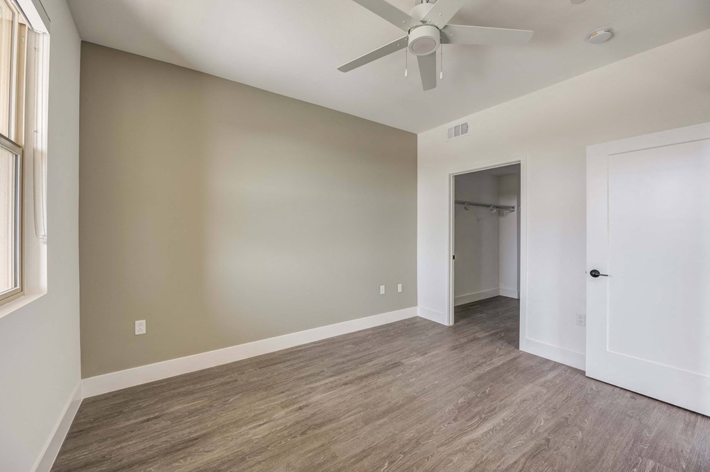 an empty living room with a ceiling fan and a door to a closet
