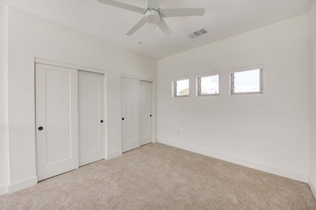 a living room with white walls and a ceiling fan