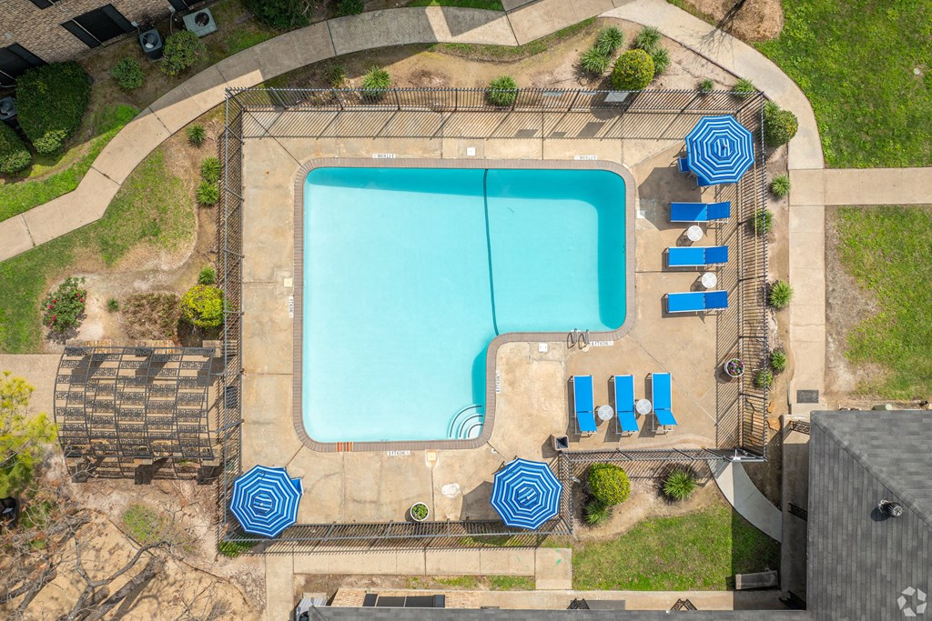 arial view of a swimming pool with blue umbrellas and chairs around it
