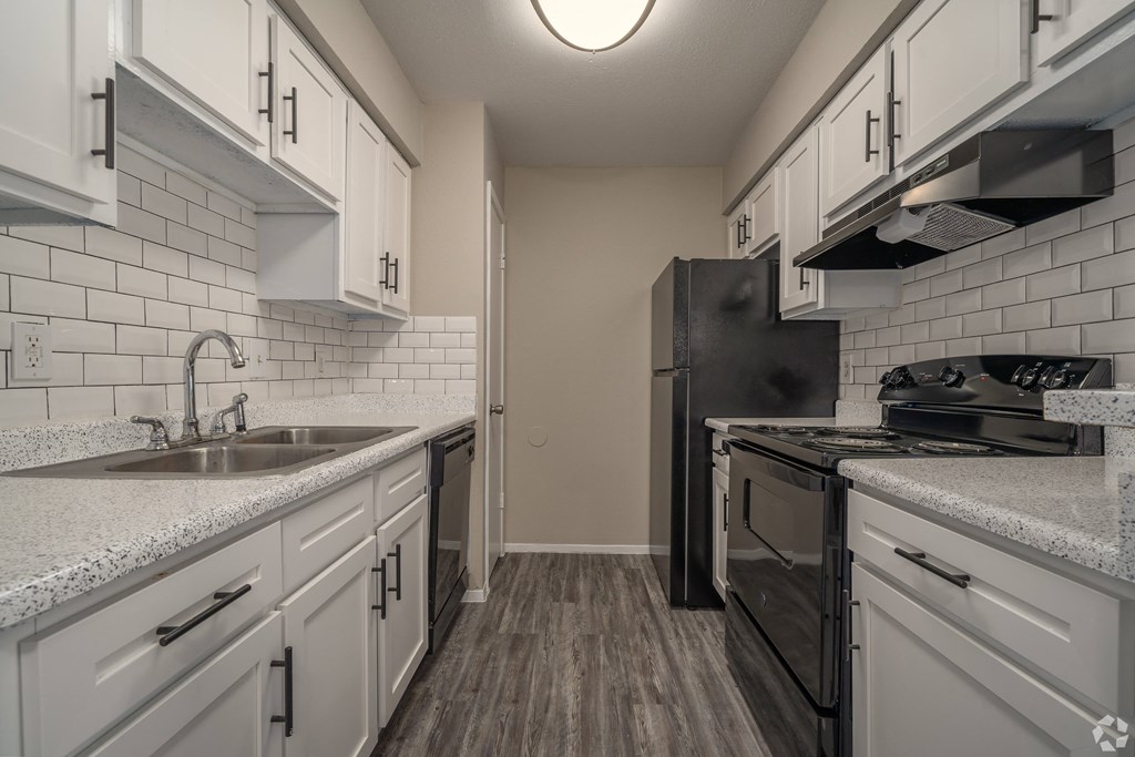 an empty kitchen with white cabinets and black appliances